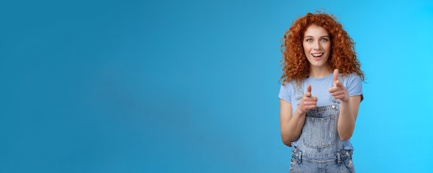 Free photo gotcha cool sassy goodlooking redhead curly woman pointing camera finger pistols cheeky introduction