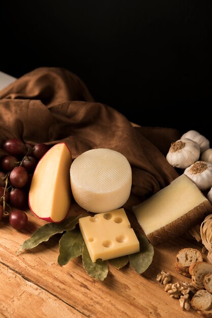 Гауда, сыр пармезан и эмменталь с ингредиентами на деревянной поверхности