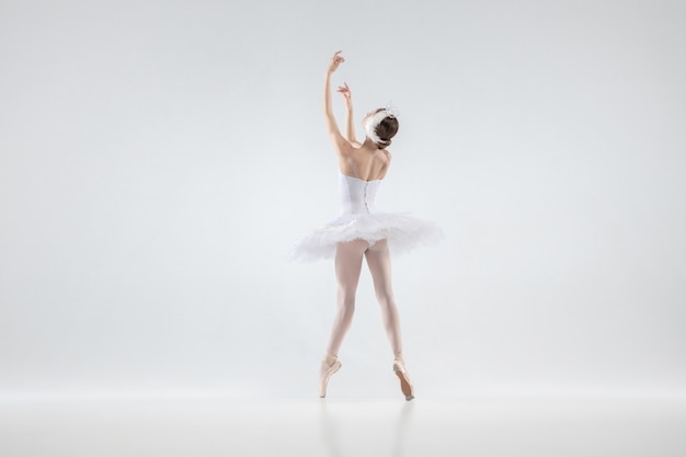 Graceful classic ballerina dancing isolated on white studio background. Woman in tender clothes like a white swan characters. The grace, artist, movement, action and motion concept. Looks weightless.