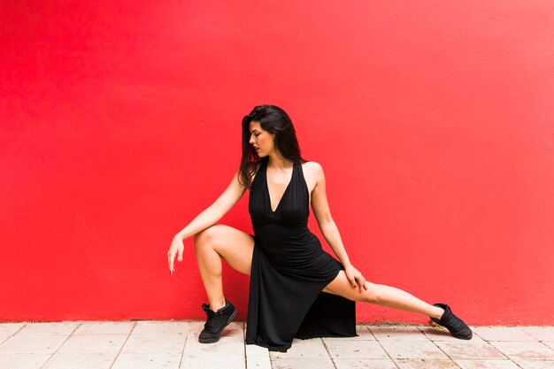 Graceful female dancer posing against red backdrop