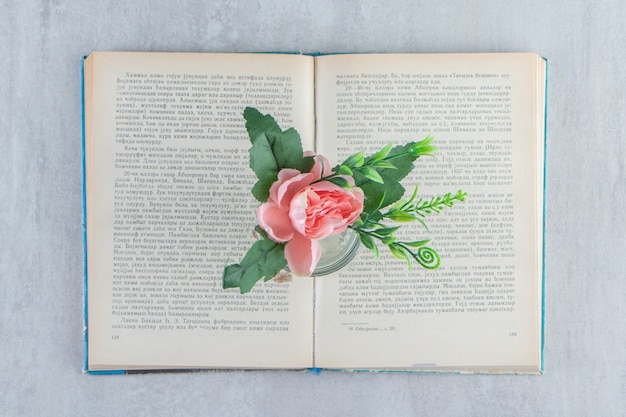 Бесплатное фото Изящные цветы в банке на книге, на белом столе.