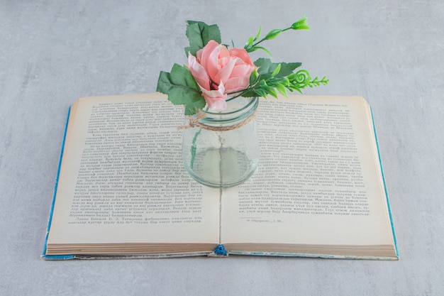 Graceful flowers in a jar on the book, on the white table.