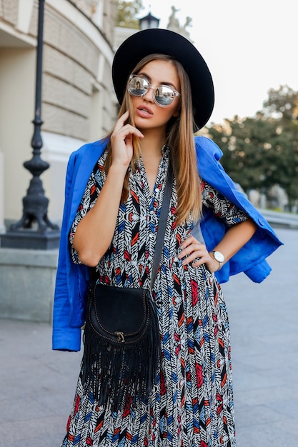 ヨーロッパでの休暇中に歩くエレガントな秋の服装の優雅な女の子。スタイリッシュなレザーバッグ。青いジャケットと黒い帽子。