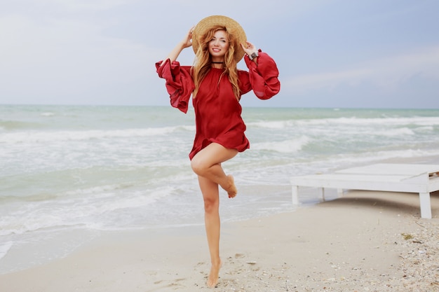 Graceful girl having fun and running on white sand. Amazing lonely beach. Full height. 