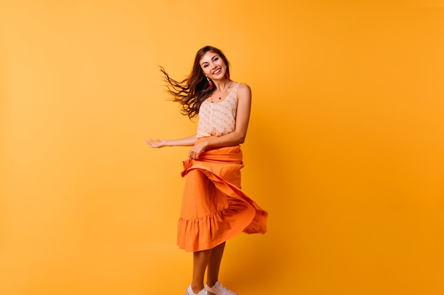 Free photo graceful girl playing with her bright summer skirt. indoor portrait of relaxed young woman dancing in studio.