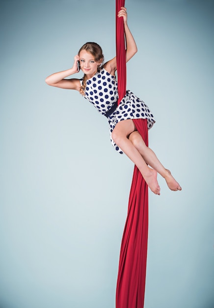 Graceful gymnast sitting with red fabrics and phone