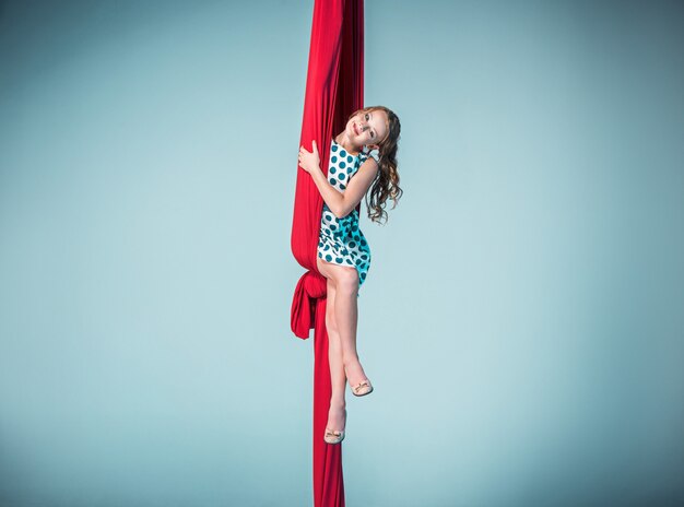 Graceful gymnast sitting with red fabrics