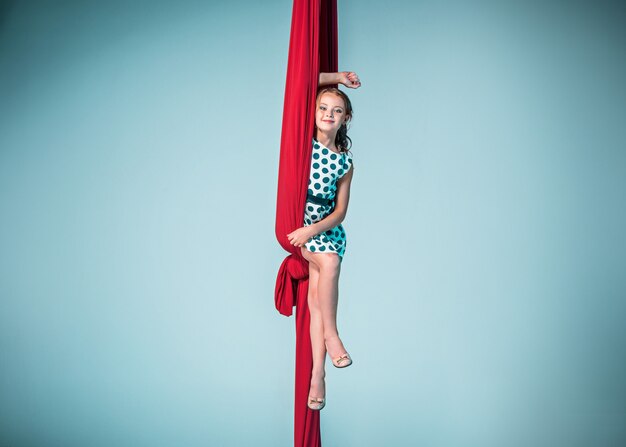 Изящная гимнастка сидит с красными тканями