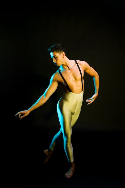 Free photo graceful male ballet dancer performing in spotlight