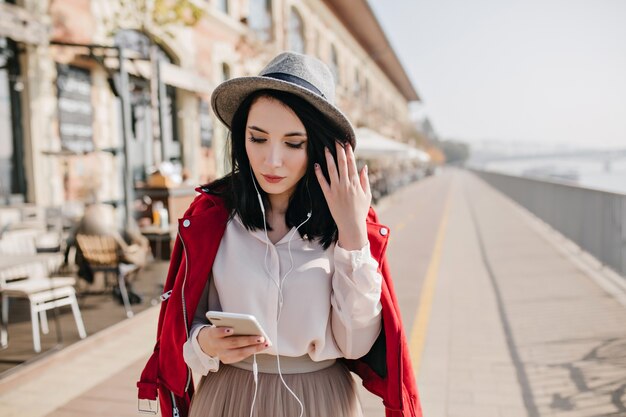 Graceful white woman looking at phone while spending time outdoor