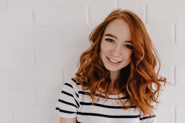 Graceful young woman with red hair expressing happiness. shy positive girl with curly hairstyle.