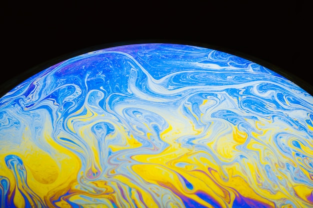 Gradient rippled multicolored soap bubble on black background