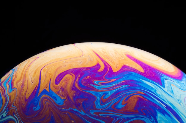 Gradient saturated colorful soap bubble on black background