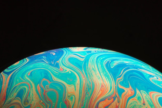 gradient varicolored smooth soap bubble on black background