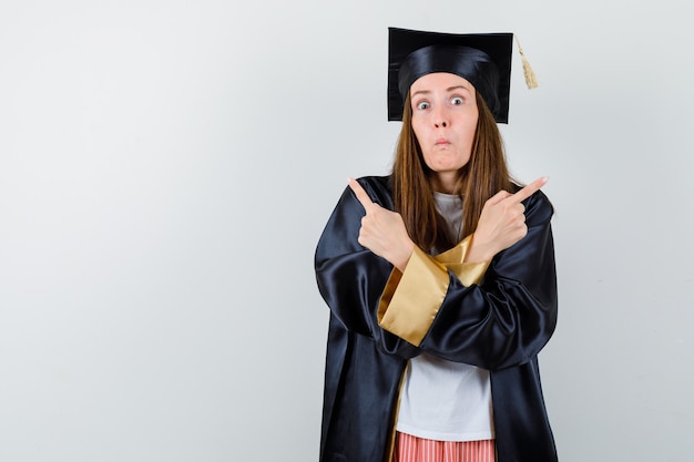 Graduate woman in casual clothes, uniform pointing up and looking puzzled , front view.