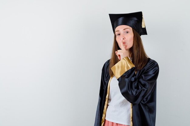 カジュアルな服装の大学院女性、沈黙のジェスチャーを示し、賢明に見える制服、正面図。