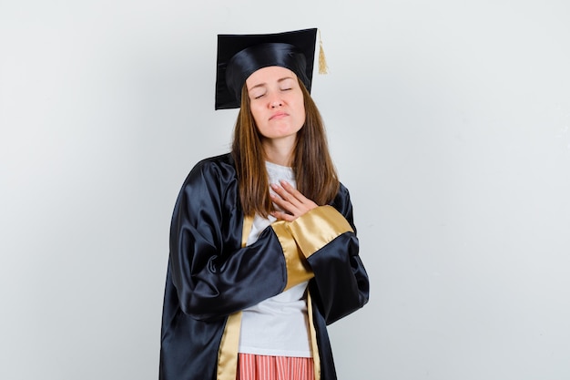 Graduate woman holding hands on chest in casual clothes, uniform and looking hopeful. front view.