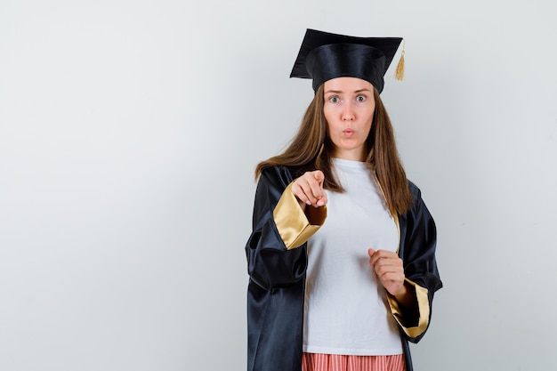 カジュアルな服装でカメラを指差して、制服を着て戸惑う大学院生の女性。正面図。