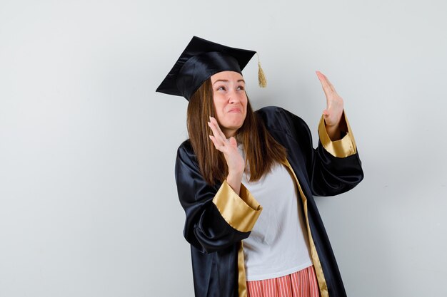 カジュアルな服装で身を守るために手を挙げている大学院生の女性、制服を着て怖がっています。正面図。