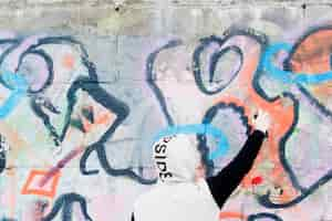 Free photo graffiti artist drawing abstract painting on wall