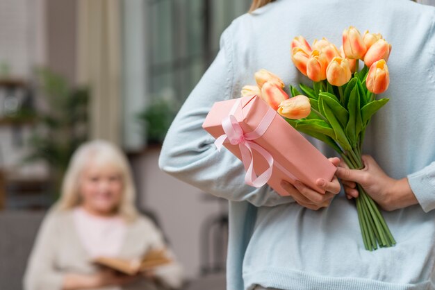 Granddaughter hiding a gift and grandmother reading