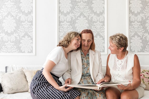 Granddaughter hugging granny looking photo album at home