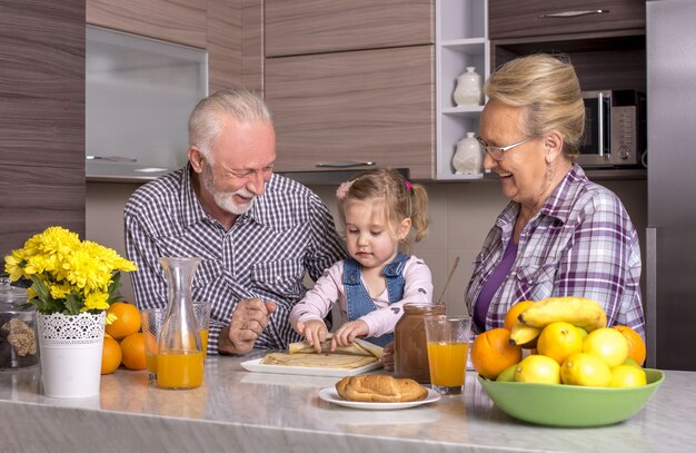 Granddaughter playing with her grandparents in the kitchen