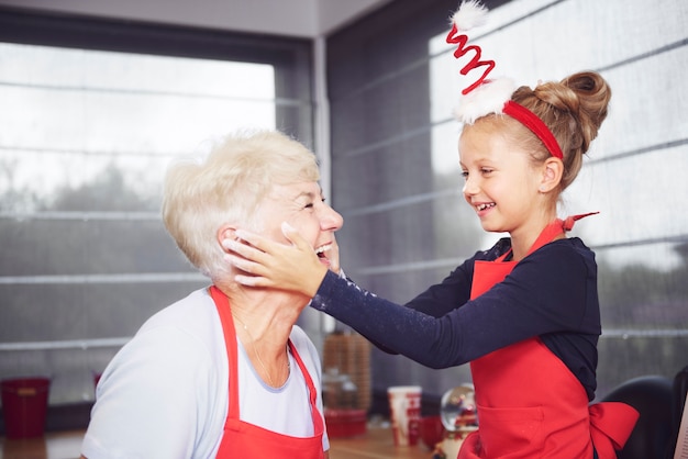 Granddaughter rubbing flour on grandmother's face