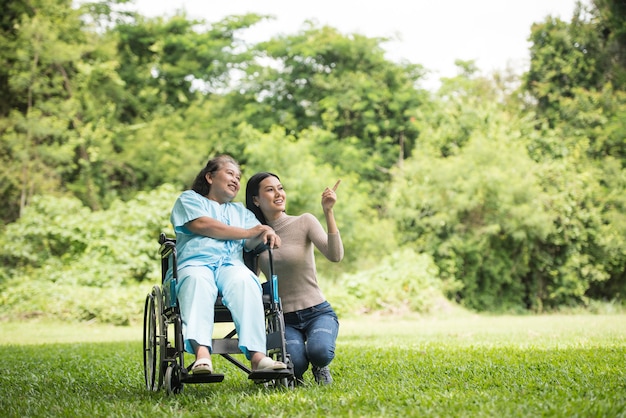 Granddaughter talking with her grandmother sitting on wheelchair, cheerful concept, happy family