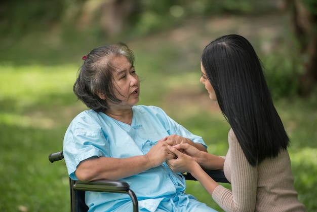 Granddaughter talking with her grandmother sitting on wheelchair, cheerful concept, happy family