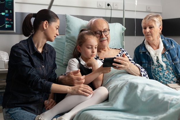 Grandfather browsing on internet with little granddaughter using modern smartphone