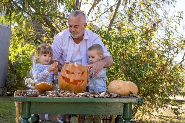 Grandfather helping children to carve a pumpkin for Halloween