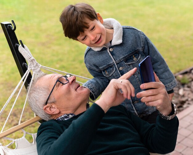 Grandfather outside with his grandkid holding a phone