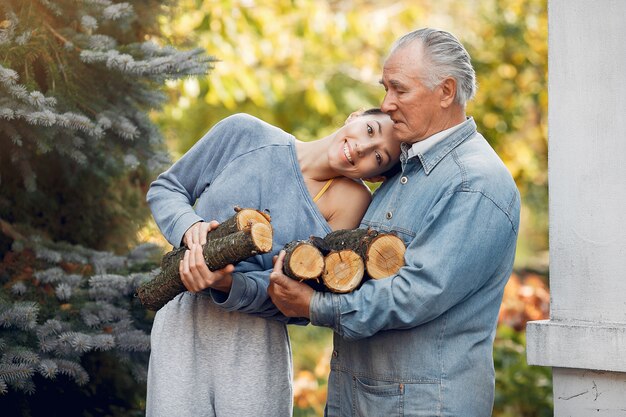 Grandfather with granddaughter on a yard with firewood in hands