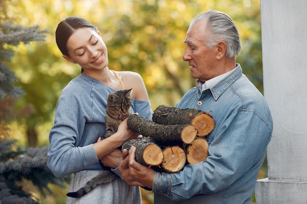 Grandfather with granddaughter on a yard with firewood in hands