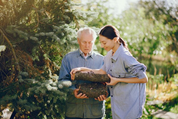 Grandfather with granddaughter on a yard with firewood in hands