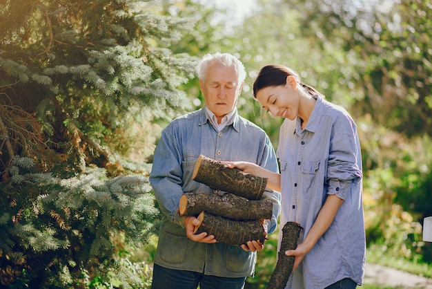 Free photo grandfather with granddaughter on a yard with firewood in hands