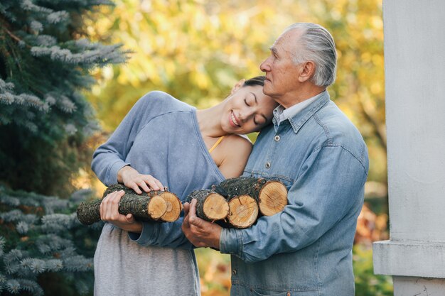 Free photo grandfather with granddaughter on a yard with firewood in hands