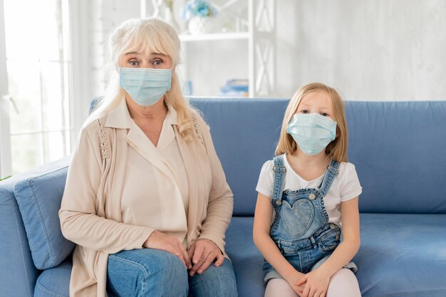 Grandma and girl with mask on couch