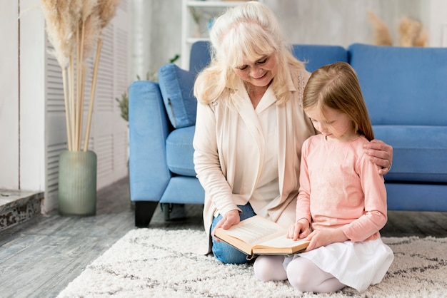 Nonna con ragazza a casa a leggere