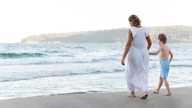 Grandmother and child walking on beach