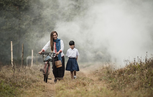 Grandmother and granddaughter are walking in the fields with bicycles.