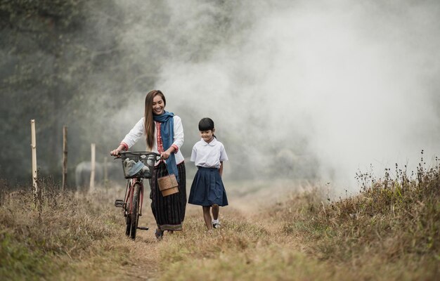 祖母と孫娘が自転車で畑を歩いています。