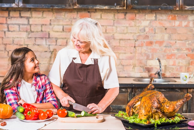 Grandmother and granddaughter cooking turkey in kitchen