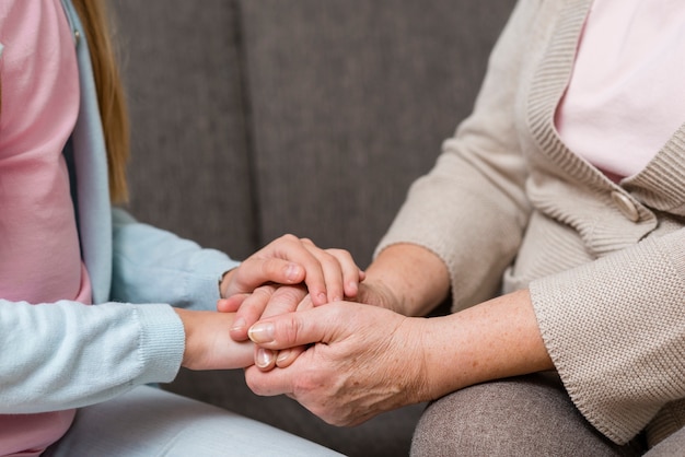 Grandmother and granddaughter holding hands close-up