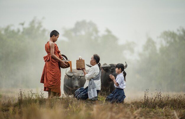 Grandmother and grandson offer food to the novices