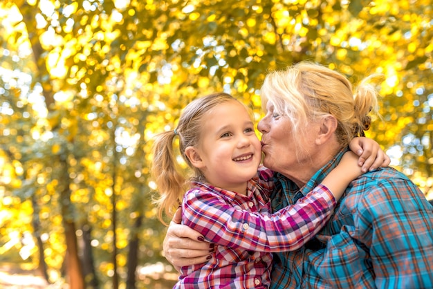 Grandmother kissing her smiling female grandchild in the park