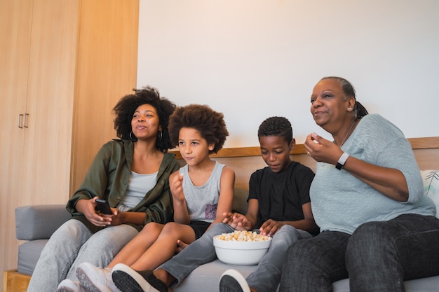 Grandmother, mother and children watching a movie at home.