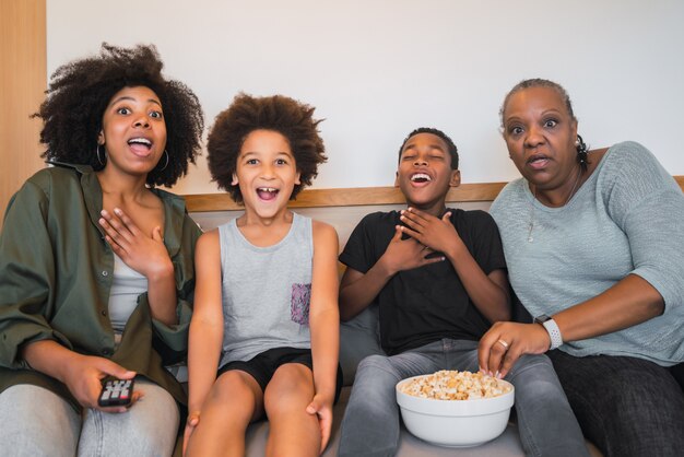 Grandmother, mother and children watching a movie at home.