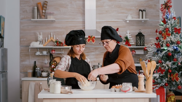 Grandmother with grandchild preparing winter homemade cookie dessert